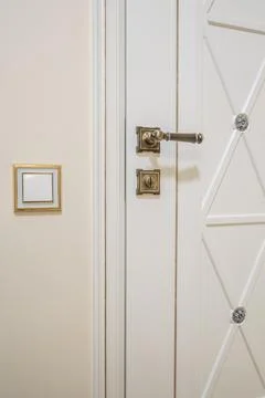 Door handle and light switch next to it in a bright room or office 스톡 사진