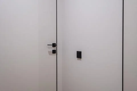 Door handle and light switch next to it in a bright room or office 스톡 사진