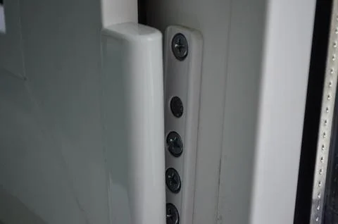 A door has a silver handle with four screws. Stock Photos