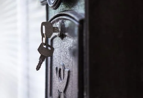 Door key inserted in keyhole ready to open black metallic mail box (letterbox Stock Photos