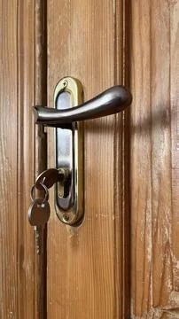 A door lock is shown with a key inserted, attached to a wooden door. The meta Stock Photos