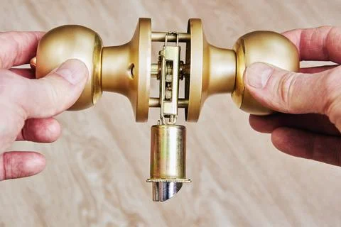 Door lockset components held by hands during assembly showing latch mechani.. Stock Photos