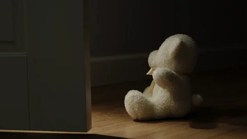 Door Opening In Front Of Plush Bear Toy Sitting On The Floor In A Dark Room Stock Footage 124623367