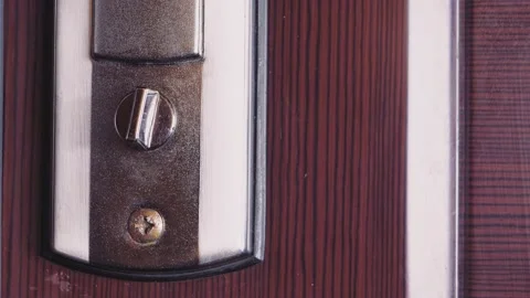 The door opens and a man's hand turns the turntable of the lock. Stock Footage 171197327