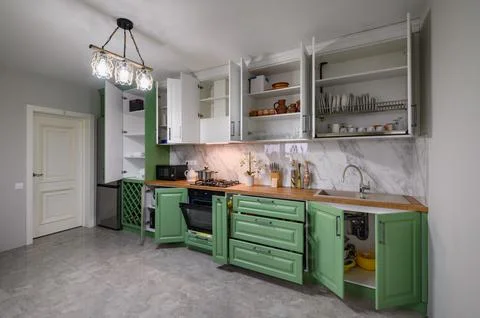 Doors open and drawers pulled out at new green and white kitchen furniture Stock Photos