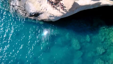 Dop down view of tourist jumping off a cliff into the ocean Stock Footage 261062199