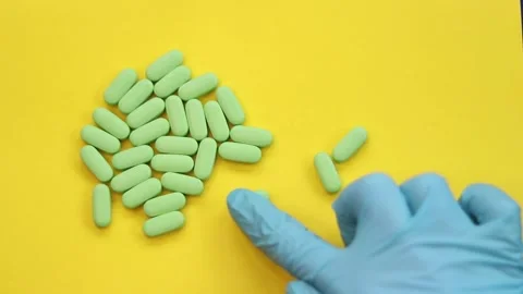Dose of tablets. A gloved hand counts out tablets Stock Footage 170124416
