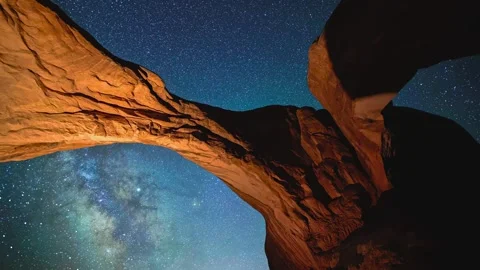 Double arch stone bridge framed against starry night sky with milky way galaxy Stock Footage 343696372