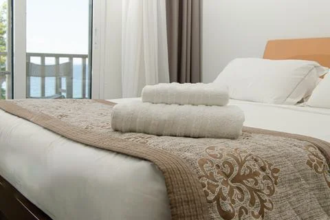 Double bed and a stack of white towels on it. Stock-Fotos