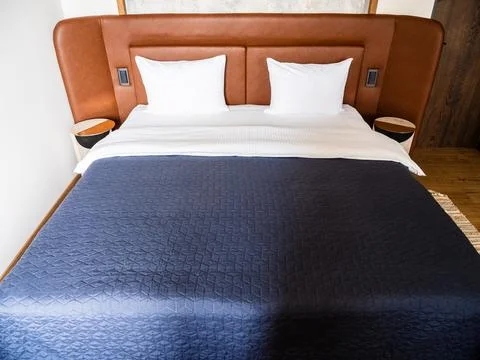 Double bed with blue bedspread, leather headboard Foto stock