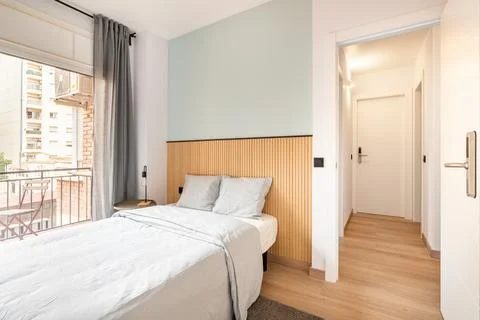 Double bed in the room, next to a large full-wall window with access to a Фото