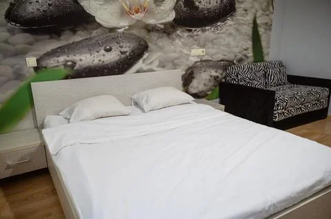 Double bed with two pillows, next to it is an armchair Stock Photos