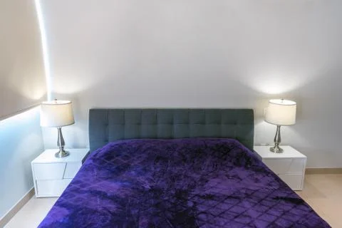 Double-bed with a violet coverlet in the interior. Modern repair. Stock Photos