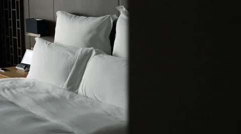 A double bed with white sheets in a hotel room-Dan Vidéo 65706873