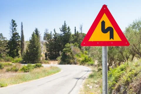 Double bend, triangular yellow warning roadsign 写真素材