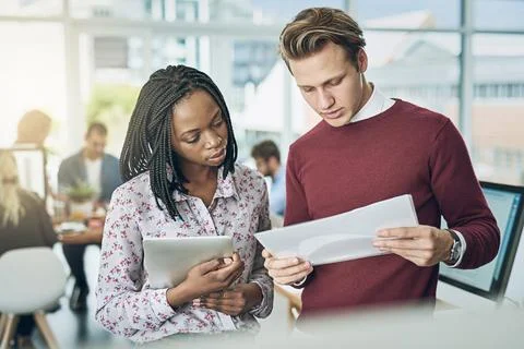 Double checking data with a trusted colleague. two young colleagues discussing Stock Photos