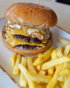 Double Cheeseburger with Fried Egg and French Fries on a Plate Stockfoto's