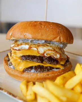 Double Cheeseburger with Fried Egg and French Fries on a Plate Photos