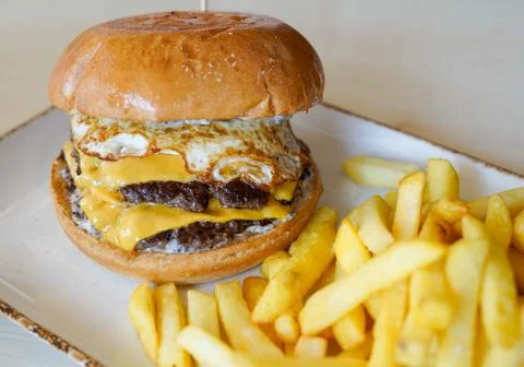 Double Cheeseburger with Fried Egg and French Fries on a Plate Stockfoto's