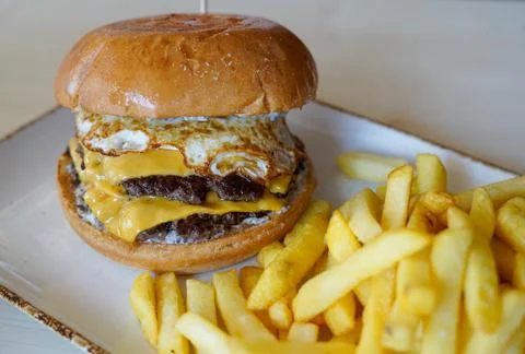 Double Cheeseburger with Fried Egg and French Fries on a Plate Photos