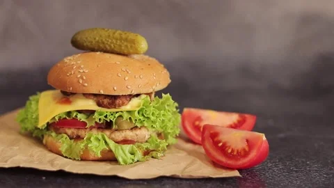 Double cheeseburger on a gray background. Juicy tasty burger on craft paper Stock Footage 255486127