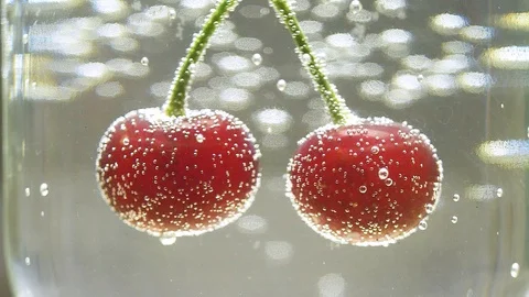 Double cherry in glass of water with bubbles on Stock Footage 100144685
