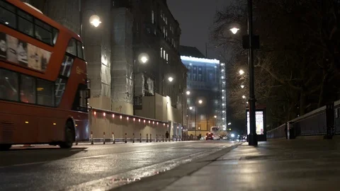 Double decker bus and cyclist drive down a rainy alley during rush hour at Stock Footage 121819287
