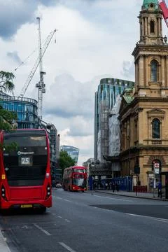 Double-decker bus driving through historic London city street with skyscrapers 스톡 사진