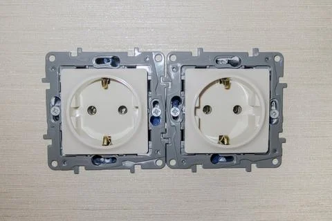 Double electrical outlet without cover on the wall with wallpaper. The color is Stock Photos