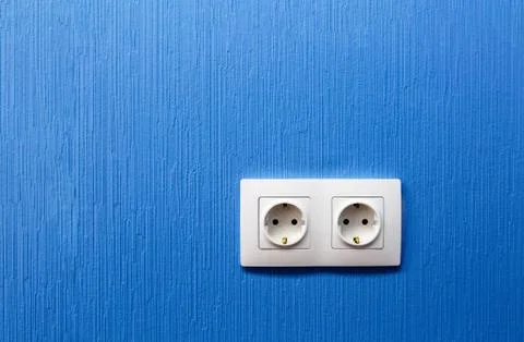 Double electrical socket and outlet on blue painted wall in the room in Stock Photos