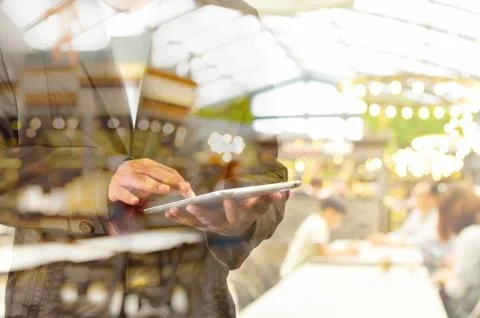 Double Exposure of Business Man using Mobile Tablet PC with Restaurant Stock Photos