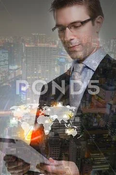 Double Exposure Of Businessman Using Touch Screen Device With Cityscape