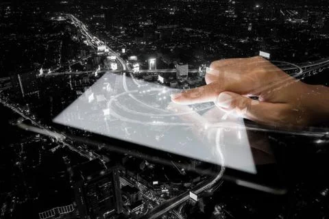Double exposure hand using tablet and city on night background Foto stock