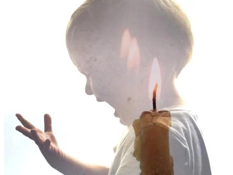 Double exposure portrait of a crying little boy and a burning candle. Stock Photos