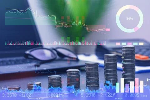 Double exposure of silver coin stacks growing like a bar graph over a laptop  Stock Photos
