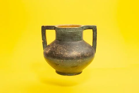 Double handled pottery vase levitating on yellow Stock Photos