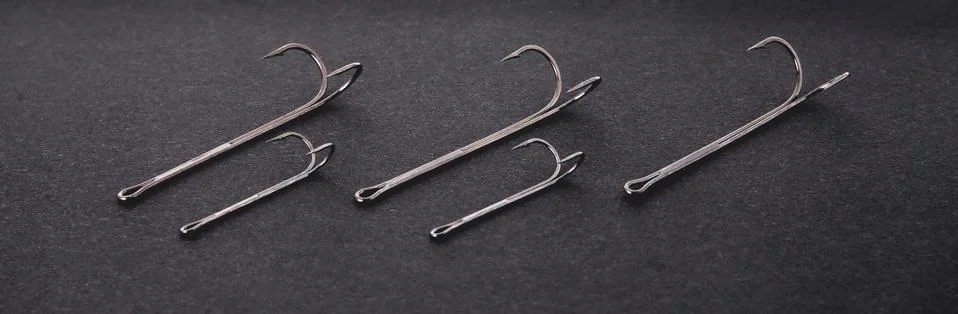 Double hooks for fishing of various sizes on a black background close-up Stock Photos