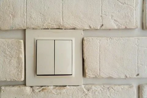 Double light switch on white brick wall interior, modern two-button wall switch Stock Photos