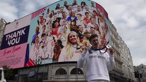 Double medalist Noah Williams poses in front of a special Picadilly circus bill Stock Footage 281728093