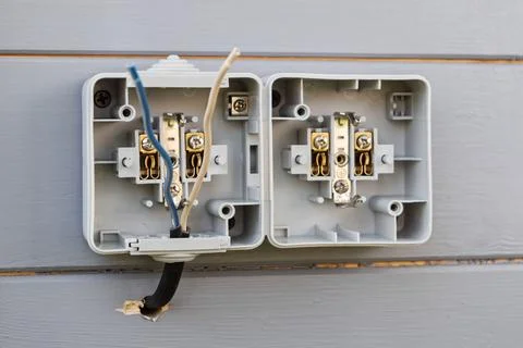 Double outdoor socket installation on gray wooden wall shows open casing and Stock-Fotos