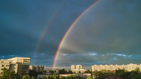 Double rainbow and light rays above urban buildings, against dark blue sky. Stock Footage 155817645