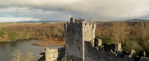 Double rainbow behind and old Irish castle. Forrest and hills.Stunning aerial Stock Footage 127920279