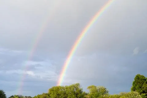 Double rainbow with blue sky background and clouds. Stock Photos