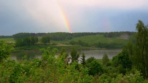 Double rainbow on a gray sky after rain over the forest lake Stock Footage 155329788