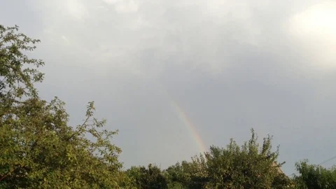 Double Rainbow In the Grey Sky and Green Trees In The Village Stock Footage 106364302