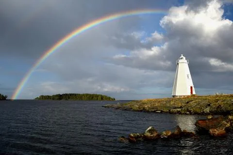 Double-Rainbow Over Classic Wooden Lighthouse on Rocky Lakeshore Stock Photos