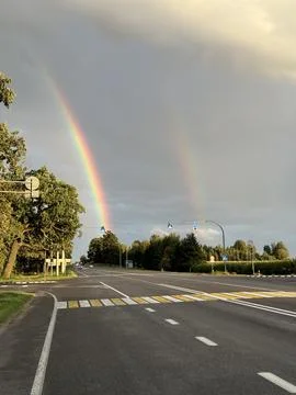 Double rainbow over empty road at sunset Stock Photos