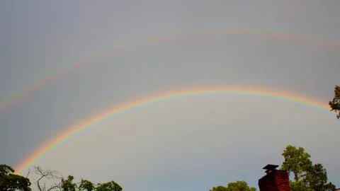 Double rainbow over tree line in Augusta, Georgia Stock Photos