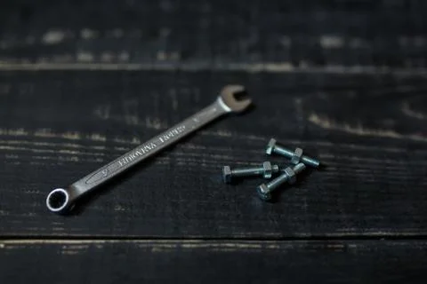 Double sided key, some nuts and bolts on black wooden background Stock Photos