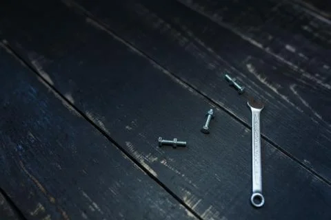 Double sided key, some nuts and bolts on black wooden background Stock Photos
